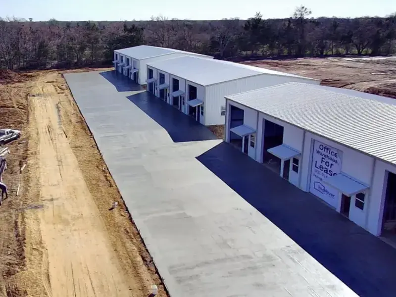 Aerial view of new commercial buildings with finished dirt work and a concrete drive