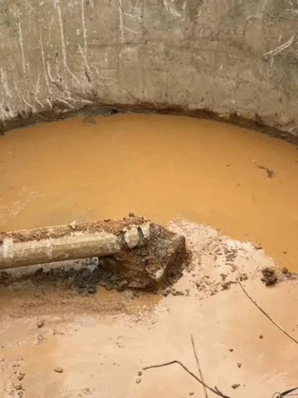 Water tank demolition: the inside of a large concrete water tank, opened up, with water and a broken pipe