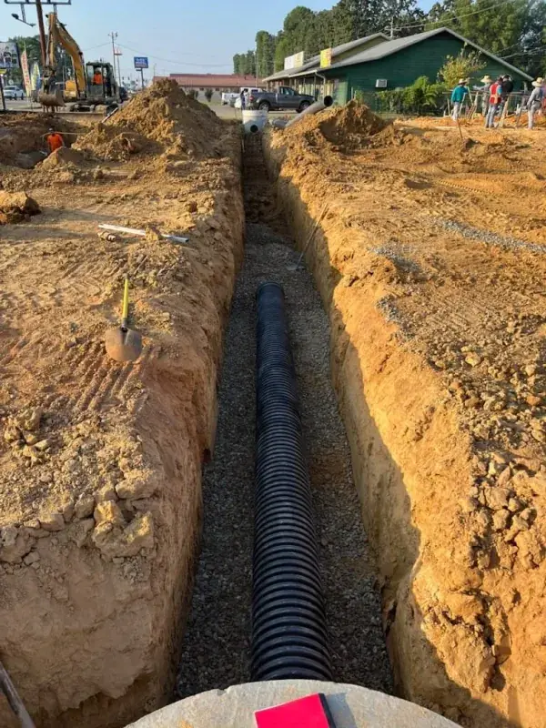 Black corrugated pipe laid in the bottom of a long trench
