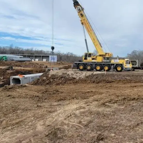 Crane on a job site with precast concrete sections staged on the ground