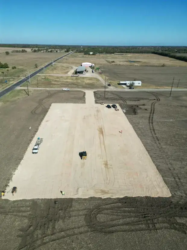 Aerial view of a gravel building pad on open farmland