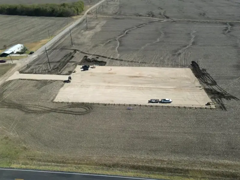 Aerial view of a rectangular gravel pad built on a large field