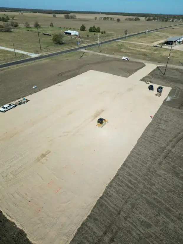 Aerial view of a long gravel pad with stakes set for construction