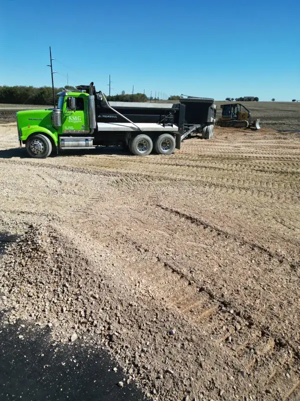Green dump truck delivering material to a graded lot