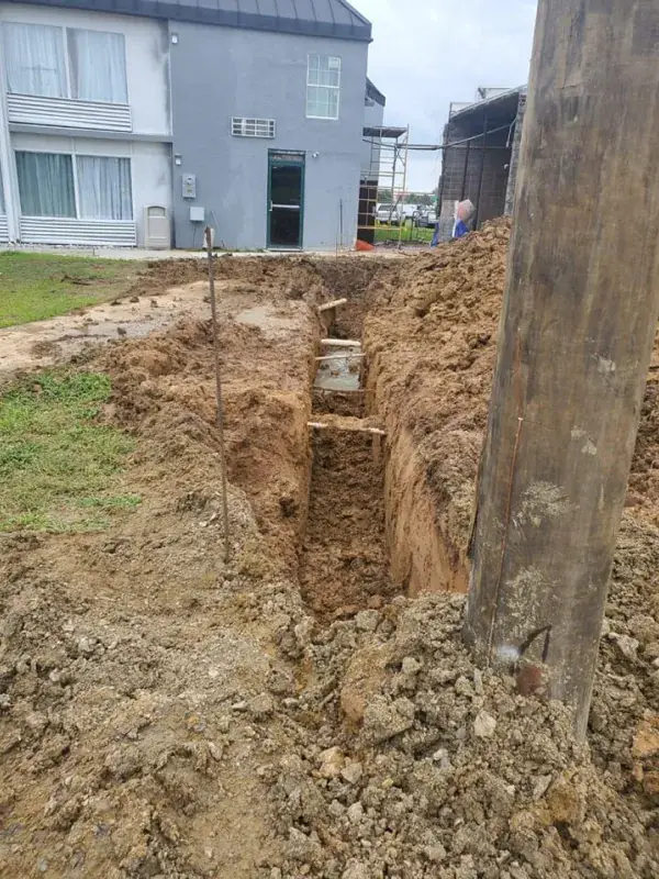 Trench dug beside a utility pole next to a building