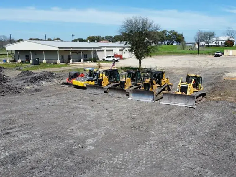 Row of Circle H dozers and equipment parked on a graded commercial pad