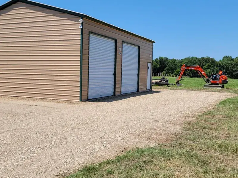 Gravel apron in front of a tan metal shop building