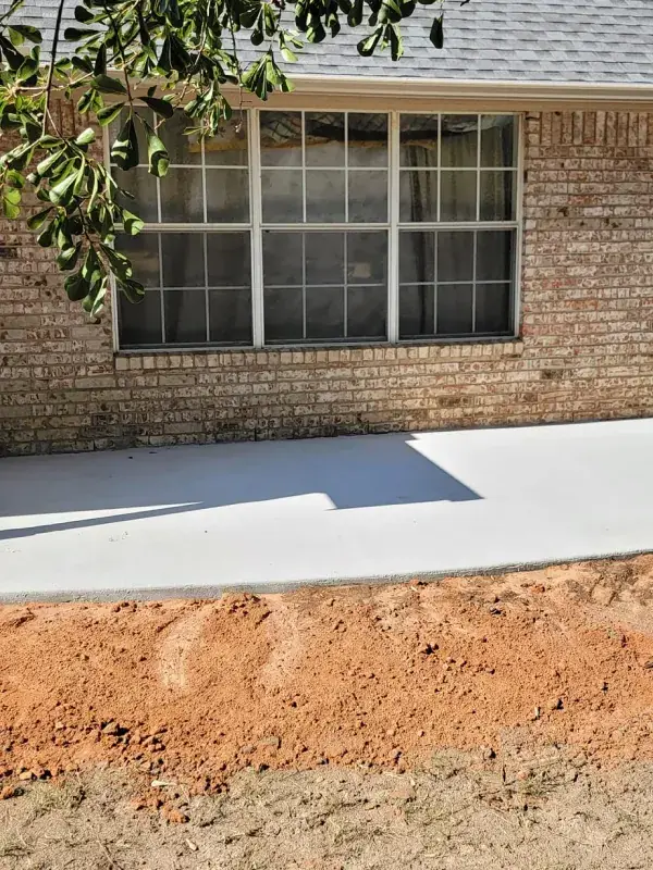 Graded dirt and concrete walkway in front of a brick home