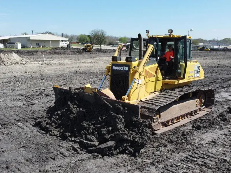 Dozer with a mud-covered blade working a wet field