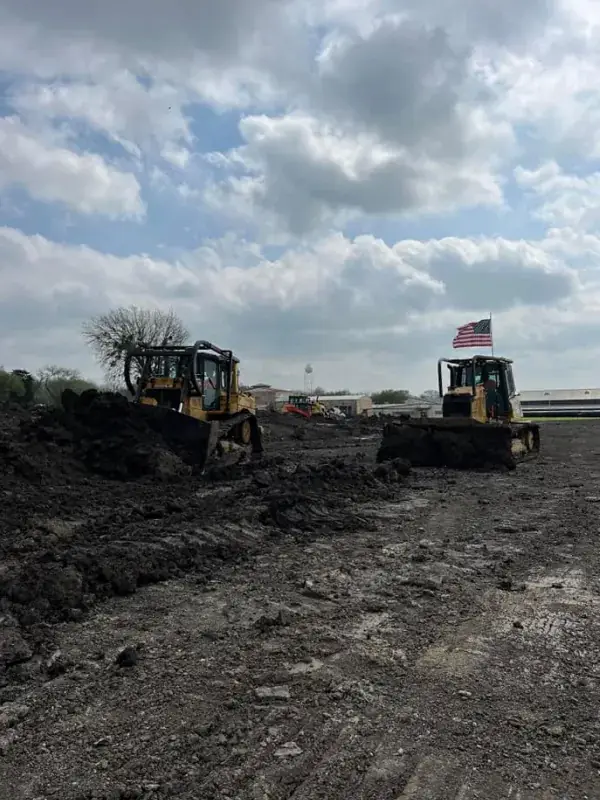 Two dozers working dark ground, one flying an American flag