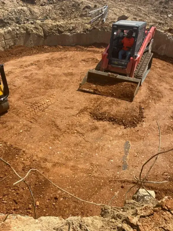 Track loader working inside a large circular pit with concrete walls