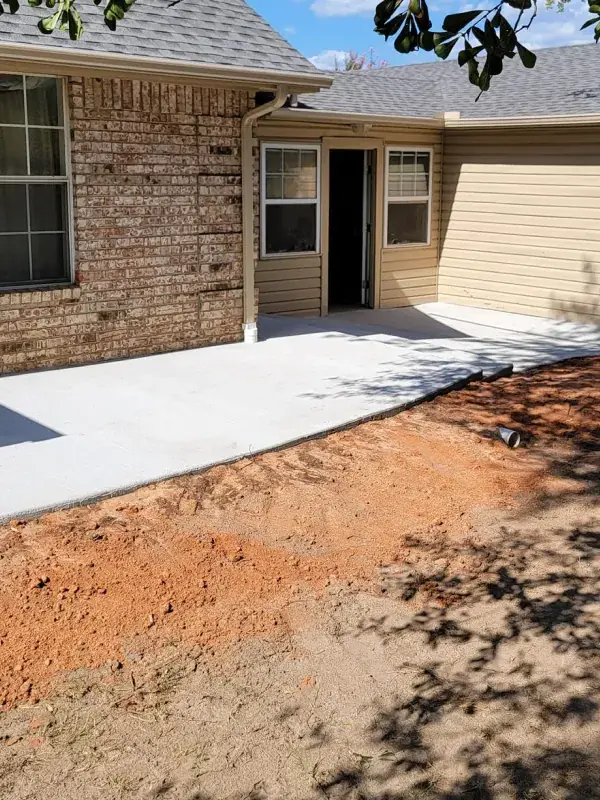 New concrete walkway and graded dirt beside a brick home