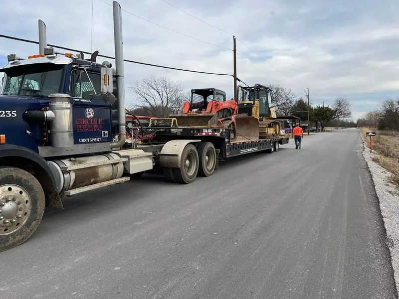 Circle H semi truck and lowboy trailer hauling a dozer down a paved road